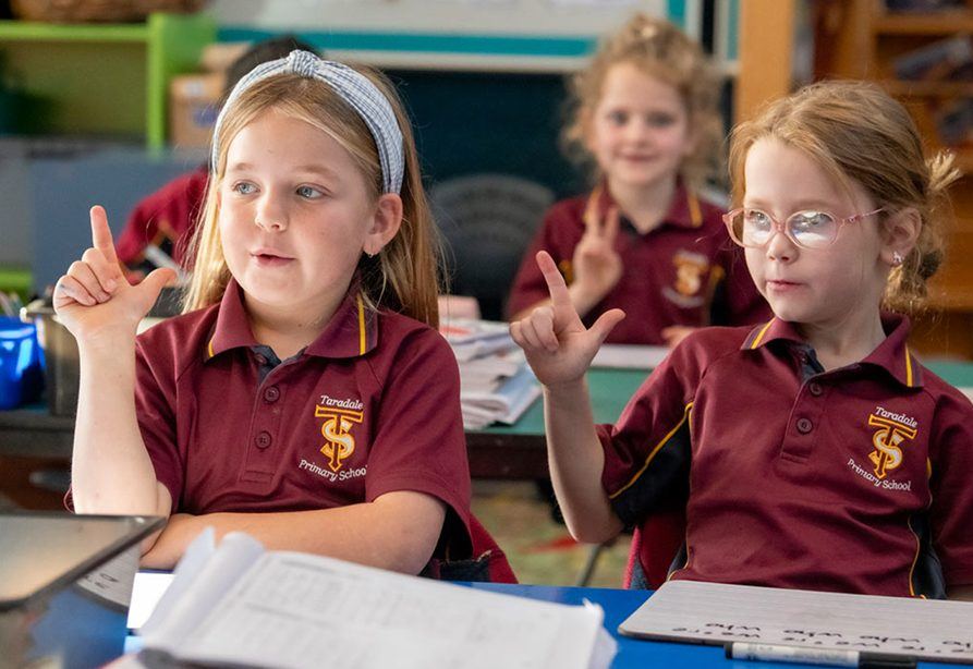 Students raising their hands to answer in class