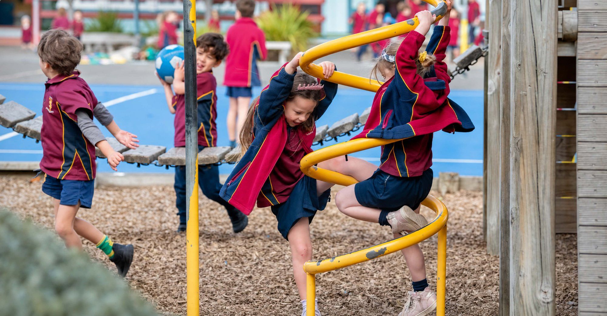Students climbing a yellow spiral frame and playing ball in the Taradale Primary playground